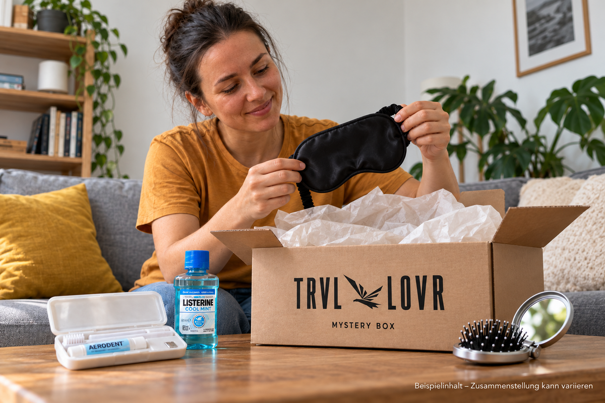 rau hält eine Schlafmaske über einer geöffneten TRVL LOVR Mystery Box mit Beispiel-Reiseutensilien